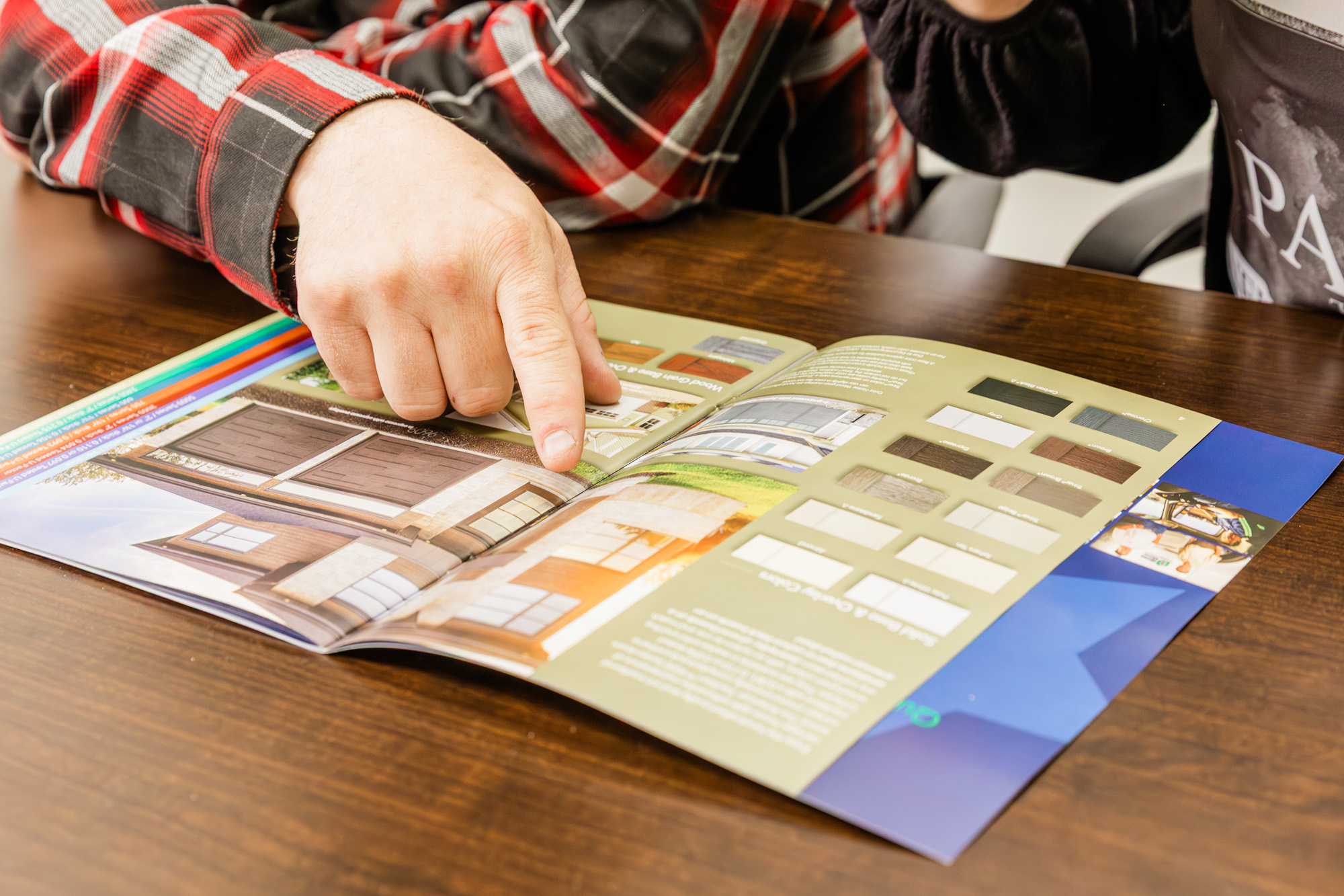 Person reviewing printed garage door color and design samples on a table.